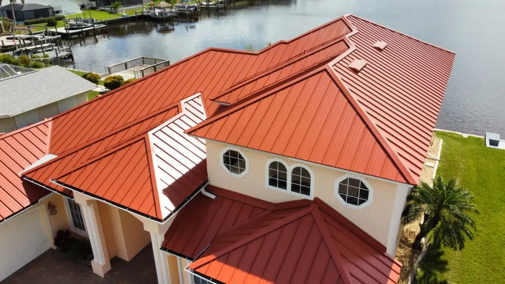 A vibrant red metal roof installed on a waterfront home with a scenic view of a canal by Giza Roofing Solutions